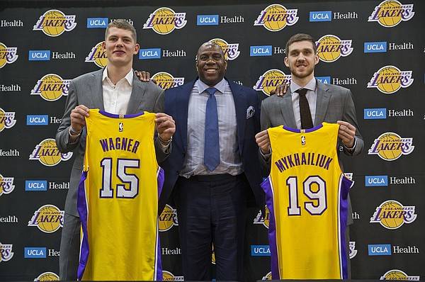 Los Angeles Lakers president of basketball operations, Earvin "Magic" Johnson, center, poses with Moritz Wagner, left, and Sviatoslav Mykhailiuk during a press conference to introduce the Lakers draft picks, in El Segundo, Calif., Tuesday, June 26, 2018. Magic Johnson is betting his job on his free-agent recruiting skills for the Los Angeles Lakers. Johnson says he will step down as the Lakers' president of basketball operations if he can't persuade an elite free agent to sign with his club within the next two summers. (AP Photo/Damian Dovarganes)