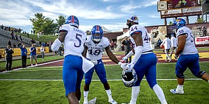 Kansas redshirt junior linebacker Denzel Feaster (18) high-fives junior defensive end Azur Kamara (5) and redshirt junior defensive end Willie McCaleb (44) as they leave the field following the team's 31-7 win over Central Michigan, the program's first road win since 2009.
