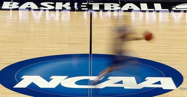 FILE - In this March 14, 2012, file photo, a player runs across the NCAA logo during practice in Pittsburgh before an NCAA tournament college basketball game. What some call the sleezy side of college basketball recruiting will be on display at a criminal trial starting Monday, Oct. 1, 2018, in New York. (AP Photo/Keith Srakocic, File)