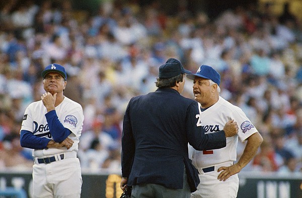 Los Angeles Dodgers third base coach Joe Amalfitano, left, waits while Dodgers manager Tommy Lasorda, right, argues with home plate umpire Fred Brocklander about a call during second inning action with the Cincinnati Reds, Tuesday, Aug. 12, 1987, Los Angeles, Calif. Lasorda continued arguing but to no avail as the ump stood his ground until Lasorda headed back to the dugout. The Dodgers won the game 7-2 anyway. (AP Photo/Lennox McLendon)