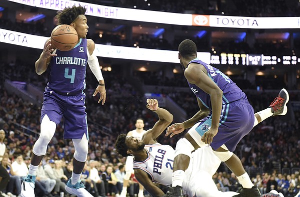 Charlotte Hornets' Devonte' Graham (4) picks up a loose ball as Philadelphia 76ers' Joel Embiid (21) falls to the floor in the second half of an NBA basketball game, Saturday, Oct. 27, 2018, in Philadelphia. The 76ers defeated the Hornets 105-103. (AP Photo/Michael Perez)