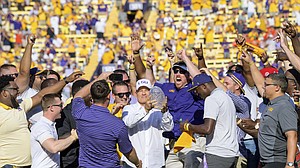 FILE — Former LSU head coach Les Miles, center, is mobbed by LSU football alumni of the 2007-8 BCS National Championship team during a halftime ceremony in an NCAA college football game against Auburn in Baton Rouge, La., Saturday, Oct. 14, 2017. Miles became the incoming head coach at the University of Kansas on Nov. 18, 2018. (AP Photo/Matthew Hinton)

