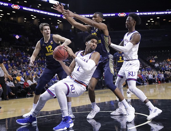 Kansas' Dedric Lawson (1) looks to pass away from Marquette's Matt Heldt (12) and Joey Hauser as teammate Marcus Garrett, right, watches during the first half of an NCAA college basketball game in the NIT Season Tip-Off tournament Wednesday, Nov. 21, 2018, in New York. 