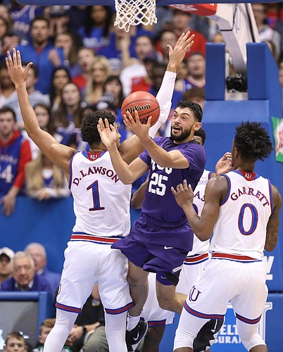 TCU guard Alex Robinson (25) tosses a shot over his head after running out of options against Kansas forward Dedric Lawson (1) and Kansas guard Marcus Garrett (0) during the first half, Wednesday, Jan. 9, 2019 at Allen Fieldhouse.