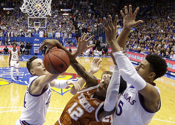 Texas guard Kerwin Roach II (12) battles for a rebound with Kansas forward Mitch Lightfoot (44) and guard Quentin Grimes (5) during the first half of an NCAA college basketball game Monday, Jan. 14, 2019, in Lawrence, Kan. (AP Photo/Charlie Riedel)