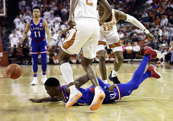 Kansas guard Lagerald Vick (24) falls to the floor past Texas guard Kerwin Roach II (12) and guard Matt Coleman III (2) as he loses control of the ball during the first half on an NCAA college basketball game in Austin, Texas, Tuesday, Jan. 29, 2019. (AP Photo/Eric Gay)