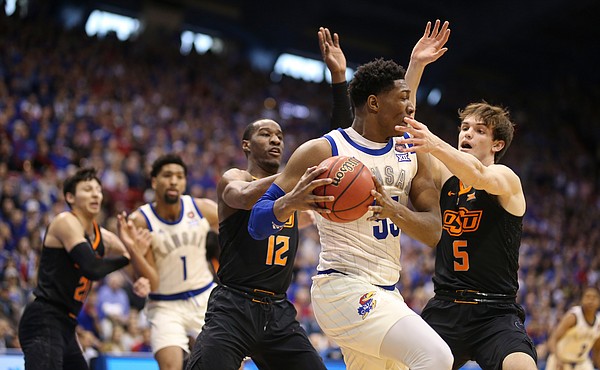 Kansas forward David McCormack (33) is hounded by Oklahoma State forward Duncan Demuth (5) and Oklahoma State forward Cameron McGriff (12) during the first half, Saturday, Feb. 9, 2019 at Allen Fieldhouse.