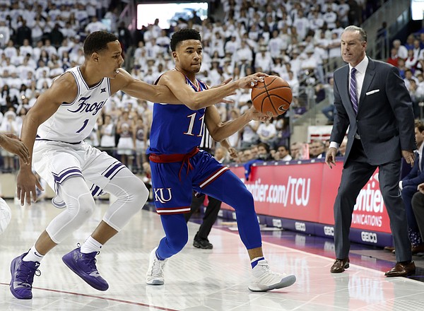 TCU guard Desmond Bane (1) attempts to strip the ball away from Kansas guard Devon Dotson (11) as TCU head coach Jamie Dixon, right, watches in the first half of an NCAA college basketball game in Fort Worth, Texas, Monday, Feb. 11, 2019. (AP Photo/Tony Gutierrez)