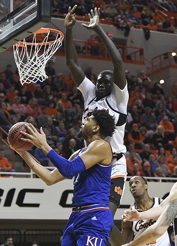 Oklahoma State forward Cameron McGriff, right, watches as Kansas guard Dedric Lawson, left, takes as shot under pressure from Oklahoma State forward Yor Anei during an NCAA college basketball game in Stillwater, Okla., Saturday, March 3, 2019. Lawson led scoring for Kansas with 20 points in the 72-67 win over Oklahoma State. (AP Photo/Brody Schmidt)