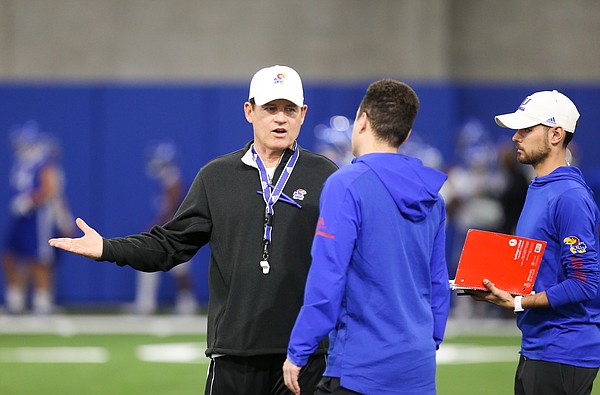 Kansas head coach Les Miles talks with members of his staff during football practice on Wednesday, March 6, 2019 within the new indoor practice facility.
