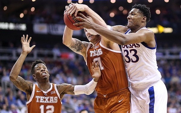 Kansas forward David McCormack (33) wrestles for a ball with Texas forward Dylan Osetkowski (21) during the second half, Thursday, March 14, 2019 at Sprint Center in Kansas City, Mo. At left is Texas guard Kerwin Roach II (12).