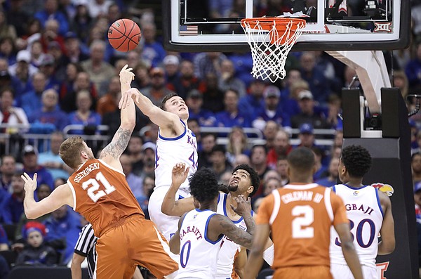 Kansas forward Mitch Lightfoot (44) rejects a shot from Texas forward Dylan Osetkowski (21) during the first half, Thursday, March 14, 2019 at Sprint Center in Kansas City, Mo.