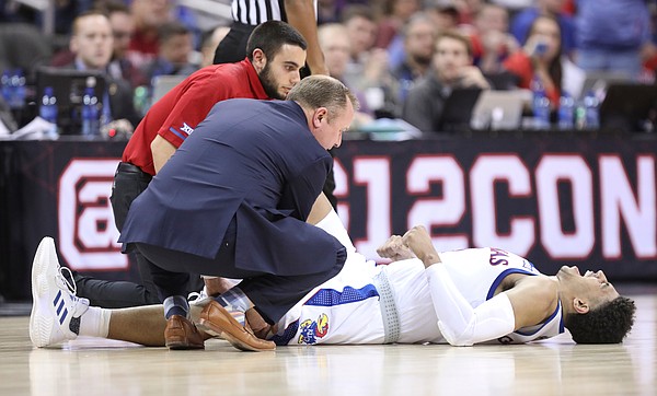 Kansas guard Quentin Grimes (5) is visited by trainers as he lies on the floor with a cramp during the second half, Friday, March 15, 2019 at Sprint Center in Kansas City, Mo.