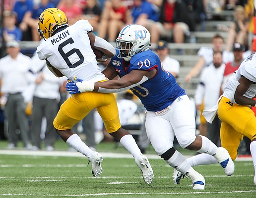 Kansas defensive tackle Jelani Brown (90) brings down West Virginia running back Kennedy McKoy (6) for a loss during the first quarter on Saturday, Sept. 21, 2019 at David Booth Kansas Memorial Stadium.