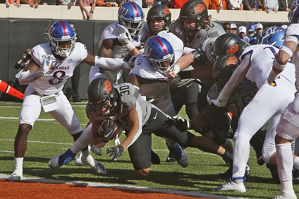 Oklahoma State running back Chuba Hubbard (30) dives into the end zone for a touchdown in front of half of Kansas cornerback Kyle Mayberry (8) and defensive tackle Caleb Sampson, center, in the first half an NCAA college football game in Stillwater, Okla., Saturday, Nov. 16, 2019. (AP Photo/Sue Ogrocki)