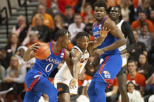 Kansas center Udoka Azubuike, right, watches as Kansas guard Marcus Garrett, left, drives the ball under pressure from Oklahoma State guard Chris Harris Jr. during the first half of an NCAA college basketball game in Stillwater, Okla., Monday, Jan. 27, 2020. (AP Photo/Brody Schmidt)