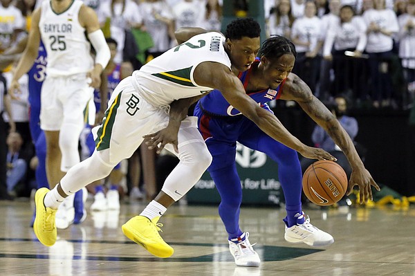 Baylor guard Devonte Bandoo, left, and Kansas guard Marcus Garrett, right, reach for the loose ball during the first half of an NCAA college basketball game on Saturday, Feb. 22, 2020, in Waco, Texas. (AP Photo/Ray Carlin)