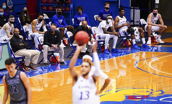 Bill Self and the Kansas bench sit socially-distanced on the sidelines as Kansas guard Tristan Enaruna (13) shoots free throws during the first half on Thursday, Dec. 3, 2020 at Allen Fieldhouse.