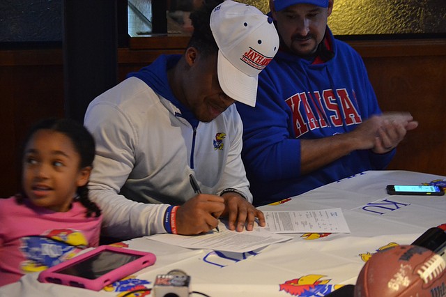 Lawrence High senior Devin Neal (middle) signs his national letter of intent while his family watches Wednesday afternoon at 23rd Street Brewery on Dec. 16, 2020. Neal, who is the top-ranked recruit in the state, signed to play football and baseball at KU.
