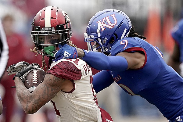 Oklahoma wide receiver Jadon Haselwood is tackled by Kansas cornerback Jeremy Webb (9) during the first half of an NCAA college football game Saturday, Oct. 23, 2021, in Lawrence, Kan. (AP Photo/Charlie Riedel)