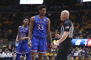 Kansas forward David McCormack (33) and guard Ochai Agbaji (30) speak with an official during the first half of the team's NCAA college basketball game against West Virginia in Morgantown, W.Va., Saturday, Feb. 19, 2022.