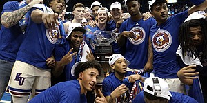 The Kansas Jayhawks huddle around the Big 12 Conference trophy after defeating Texas in overtime on Saturday, March 5, 2022 at Allen Fieldhouse. The win gave Kansas a share of the Big 12 conference title.