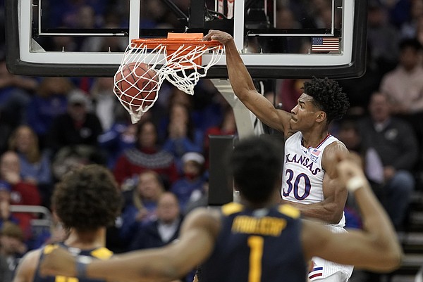 Kansas guard Ochai Agbaji (30) delivers on a lob jam as the West Virginia players watch during the second half on Thursday, March 10, 2022 at T-Mobile Center in Kansas City.