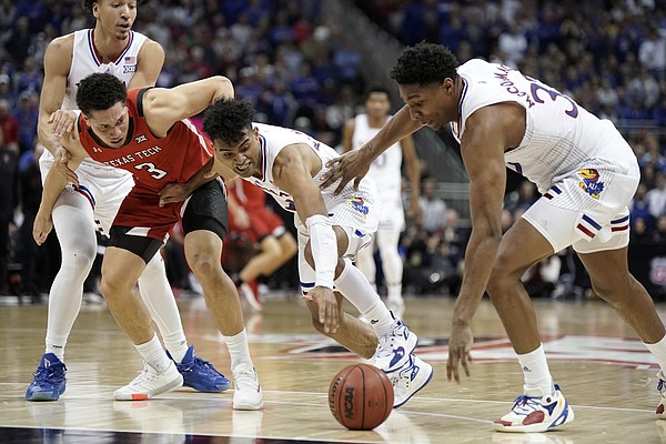 Kansas guard Remy Martin (11), Kansas forward David McCormack (33) and Texas Tech guard Clarence Nadolny (3) wrestle for a loose ball during the second half of the Big 12 Tournament championship game on Saturday, March 12, 2022 at T-Mobile Center in Kansas City. Also at left is Kansas forward Jalen Wilson (10).