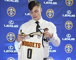 One of the Denver Nuggets' selections from the NBA Draft, Christian Braun, looks over his jersey after being introduced to the media during a news conference Monday, June 27, 2022, in Denver. (AP Photo/David Zalubowski)



