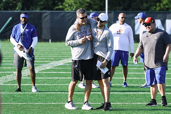 KU assistant coaches Jim Panagos, left, and Jordan Peterson share a laugh during the Jayhawks' practice on Friday, Aug. 12, 2022. 