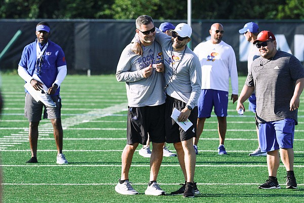 KU assistant coaches Jim Panagos, left, and Jordan Peterson share a laugh during the Jayhawks' practice on Friday, Aug. 12, 2022. 