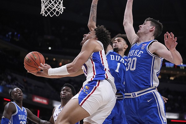 Kansas forward Jalen Wilson, left, drives to the basket past Duke center Dereck Lively II (1) and center Kyle Filipowski (30) during the second half of an NCAA college basketball game, Tuesday, Nov. 15, 2022, in Indianapolis. (AP Photo/Darron Cummings)